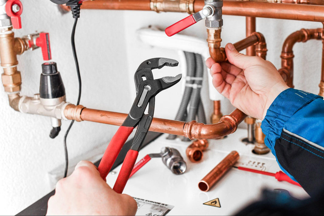 Plumber Working on Copper Pipes Under a Sink
